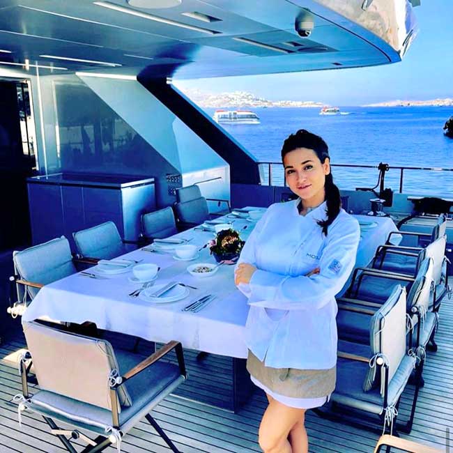 Estela Calzón delante de una mesa preparada para servir la comida en un barco